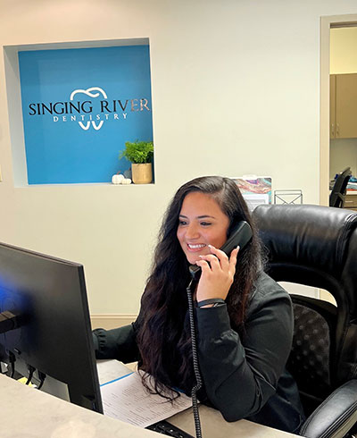 A receptionist scheduling the appointment at Singing River Dentistry.