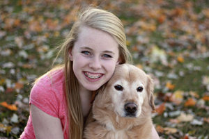 A girl with braces smiling with her dog.