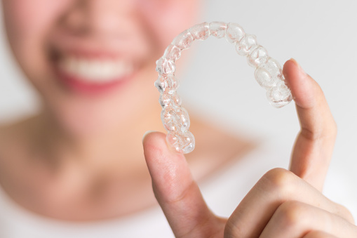 A hand holding a set of Invisalign clear braces at Singing River Dentistry in Athens, AL