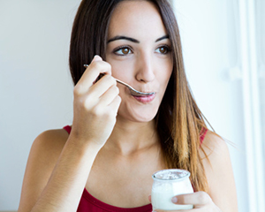 Woman eating yogurt snack before appointment at Singing River Dentistry in Tuscumbia, AL