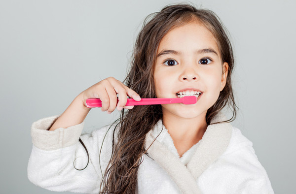 Young girl brushing her teeth after visiting Singing River Dentistry.