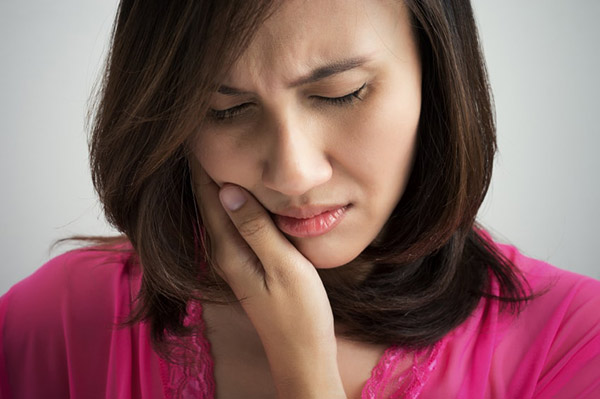 Woman holding her jaw in pain before TMJ treatment at Singing River Dentistry in Athens, AL